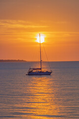 Wall Mural - Vertical photo of a boat in the sea at sunset