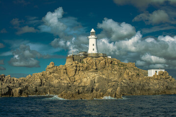 Poster - Scenic view of a white lighthouse on a cloudy sky background