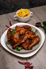 Wall Mural - Vertical shot of grilled chicken legs with greens on blurry backround with chilli peppers and pasta