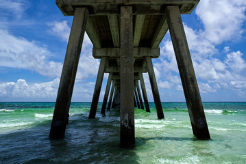 Sticker - Low angle shot of the bottom of a pier with sea water ans the sky in the background