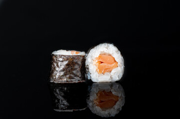 Poster - Tasty sushi rolls with salmon isolated on a black background