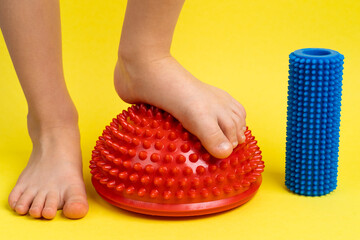 children's feet with a red balancer on a light yellow background, treatment and prevention of flat feet, valgus deformity of the foot