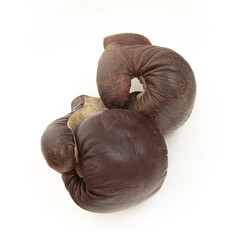 Old boxing gloves hanging on a white wall, close up.