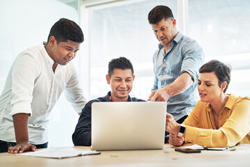 Wall Mural - Scouting the net for some more inspiration. Shot of a group of businesspeople working together on a laptop in an office.