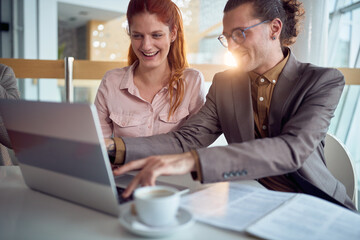 Wall Mural - A young businessman is having a good time with female colleague while they enjoying a laptop content in the company building together. Business, people, company