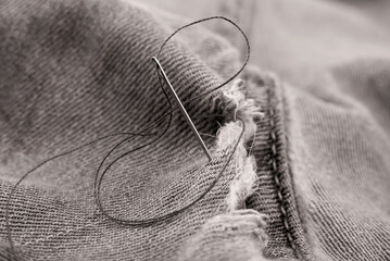 hole in jeans. needle with thread for darning jeans. tools for work dressmaker, seamstress fashion d