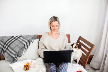 Wall Mural - Happy middle aged woman using her laptop on the sofa at home