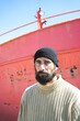 © javiemebravo - bearded sailor man with serious expression is looking intently at camera, wears turtleneck sweater and wool hat