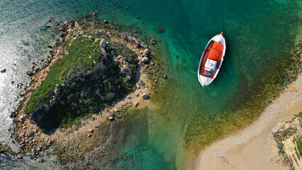 Wall Mural - Aerial top view photo of red traditional wooden fishing boat anchored in Aegean island destination port with emerald sea