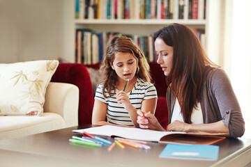 Wall Mural - Trying to figure it out together. Shot of a beautiful mother helping her adorable daughter with her homework at home.