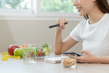 Wall Mural - Diet, Dieting hand of asian young woman working, write diet plan right nutrition with eat fresh vegetables salad is food for good health not eat junk food. Nutritionist female, Weight loss of healthy.