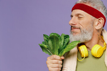 Wall Mural - Side view profile happy excited fun elderly gray-haired bearded man 40s years old in headband khaki t-shirt towel smell spinach leaves isolated on plain pastel light purple background studio portrait.