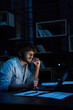 © insta_photos - Focused young indian ethnic business man, student or web designer working on laptop computer late at night at home or in dark office thinking watching webinar learning online course sitting at desk.