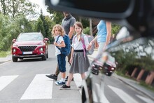 Group Of School Children Goes Through The Pedestrian Crossing In The Street, Right In Front Of The Car