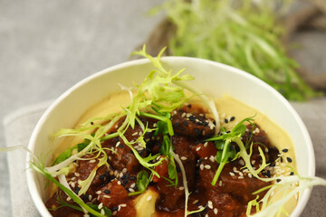 A traditional Hungarian dish is bograch or thick meat red goulash with lentil puree, served in eco paper bowl on a gray background. Restaurant food delivery service and daily ration concept.