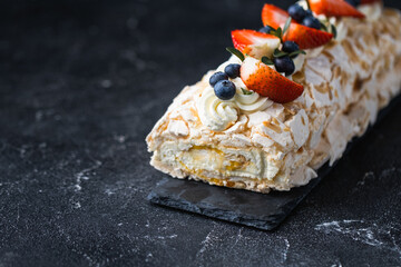 Canvas Print - Meringue roll decorated with strawberries and blueberries on the black background