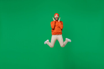 Poster - Full body young happy overjoyed excited fun cool caucasian man 20s wear orange sweatshirt hat jump high hold face celebrate isolated on plain green background studio portrait People lifestyle concept