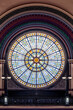 An ornate and enormous round stained glass rose window illuminates the Grand Hall of Union Station, a train station built in 1888 in downtown Indianapolis, Indiana.