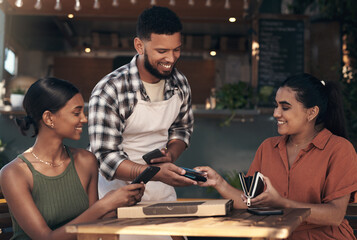 Wall Mural - Dont worry, Ive got this one. Shot of two young women sitting at a restaurant and using a credit card machine to pay for their meal.