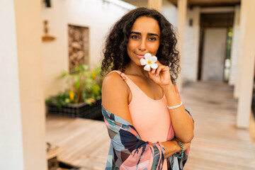 Wall Mural - Blissful woman with tropical flower  in hand posing in luxury spa hotel. Spa and body care concept.