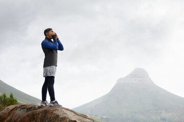 Waiting for the echo.... Shot of a young man shouting on a mountain top.