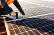 © dusanpetkovic1 - Close up of a handyman installing solar panels on the roof.