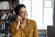 © fizkes - Cheerful young Black entrepreneur girl in stylish glasses talking on mobile phone with happy toothy smile, speaking on cellphone to client, negotiating on business project, enjoying telephone call