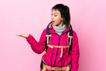 Wall Mural - Young mountaineer girl with a big backpack over isolated pink background holding copyspace imaginary on the palm