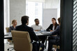 © fizkes - Concentrated serious diverse different generations people listening to Caucasian female colleague sharing corporate news, brainstorming interesting ideas or discussing working issues in modern office.