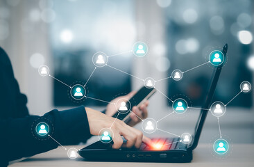 Hand using laptop to play social media, a mobile phone with a notification people icon,Social Distancing ,Working From Home concept,international consulting company. Social networking hologram icons.
