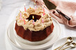 A red velvet bundt cake with liquor icing and birthday candles on white plate on marble surface