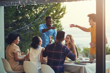 You got that right buddy. Shot of a group of friends enjoying a meal and drinks together around a table at a gathering outdoors.