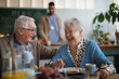 © Halfpoint - Smiling elderly woman and man enjoying breakfast in nursing home care center.