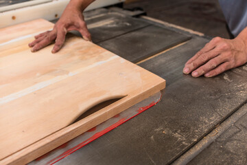 Trimming a piece of plywood intro exact measurements with a cabinet table saw. At a furniture making factory.