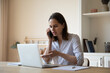 © fizkes - Woman looks at laptop makes order on-line, talks to sales manager on smartphone, discuss purchase, buy remotely, work from home office, negotiates, answers questions provide assistance on phone call