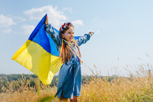 Girl Wearing National Dress And Wreath Of Flowers Holding Flag Of Ukraine