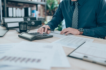 Accountant working on calculator to calculate company data, document and report on desk office. Accounting business concept.