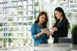 © Phushutter - Two Asian female managing directors discussing ideas of project on digital tablet, working together with colleagues.