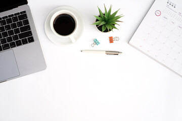Wall Mural - Workspace office business and education concept on white table desk background with laptop computer and blank notepad, coffee cup and green plant, calendar, Top view with copy space, flat lay
