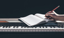 A Man Plays The Piano And Writes In A Notebook In The Dark.