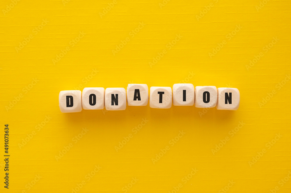Donation word over wooden blocks, yellow background. Charity concept
