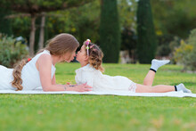 Daughter Kisses On Her Mother's Nose In The Park Outdoors