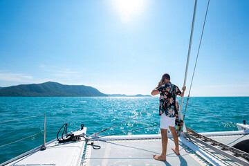 Portrait of Caucasian man enjoy luxury lifestyle catamaran boat sailing with looking at beautiful nature sea at summer sunset. Handsome male relaxing outdoor activity on tropical travel vacation trip