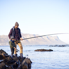 Sticker - Looks like you got something. Shot of a cute little boy fishing with his father by the sea.