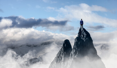 Wall Mural - adventurous man hiker standing on top of icy peak with rocky mountains in background. adventure comp