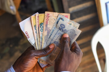 Hands holding spread of multiple Nigerian naira notes, cash, currency or money in an outdoor environment