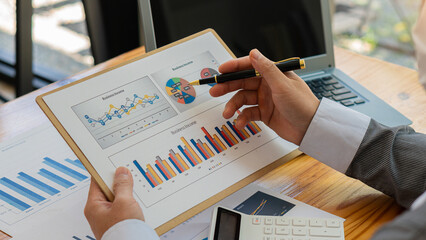 Businessman holding a financial graph, a document with financial statistics, stock images, discussion and data analysis, charts, and graphs. accounting concept