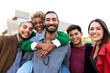 © Daniel - Portrait of group of diverse multiracial friends looking at camera. Black woman on piggy back ride with male friend.