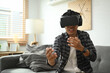 © Prathankarnpap - Asian man wearing virtual reality glasses playing simulation boxing game in living room.