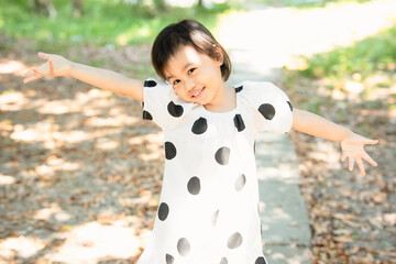 Wall Mural - 4 years old cute baby Asian girl spreading hands, have fun in park.